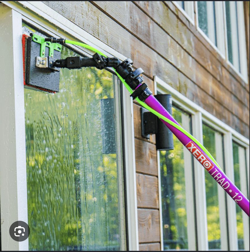 Cleaning home windows with a XERO pure-water pole, water sheeting down the glass